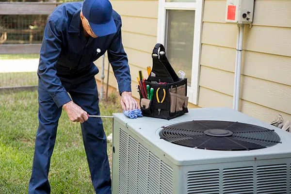 Stock photo of an HVAC technician inspecting a residential outdoor condenser