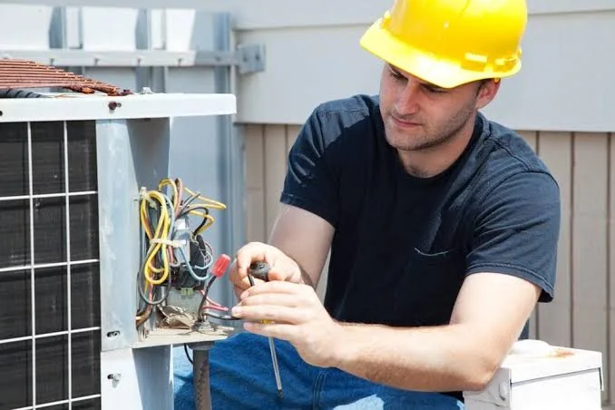 Stock photo of a technician diagnosing an outdoor air-conditioning unit