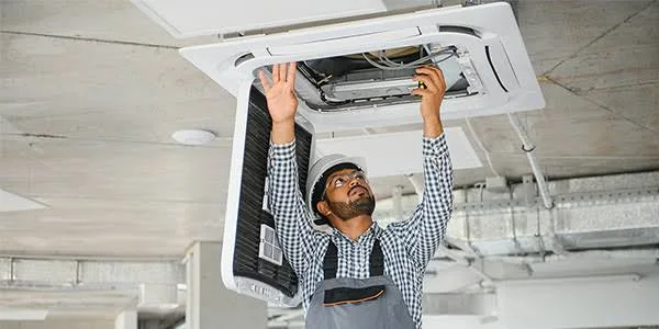 Stock photo of a technician working on a ceiling-mounted HVAC system