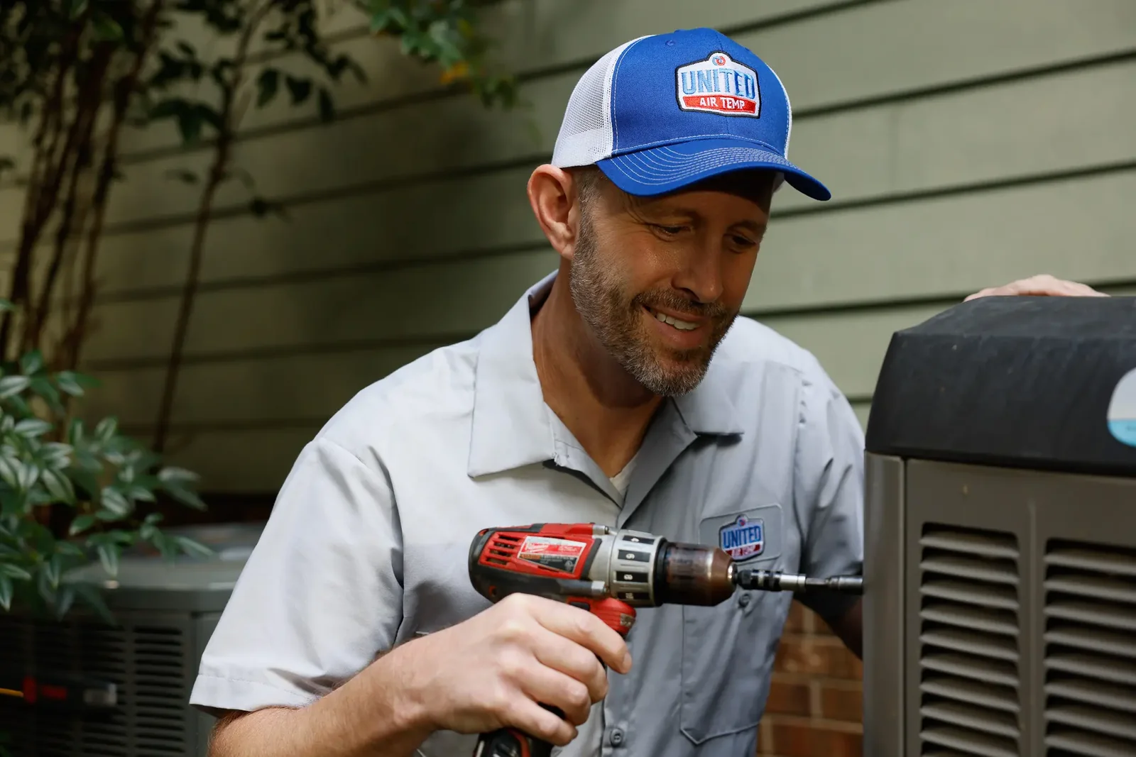 Stock photo of a technician servicing a residential outdoor cooling system