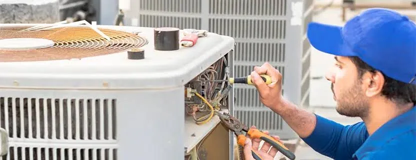 Stock photo of a technician repairing a residential outdoor condenser