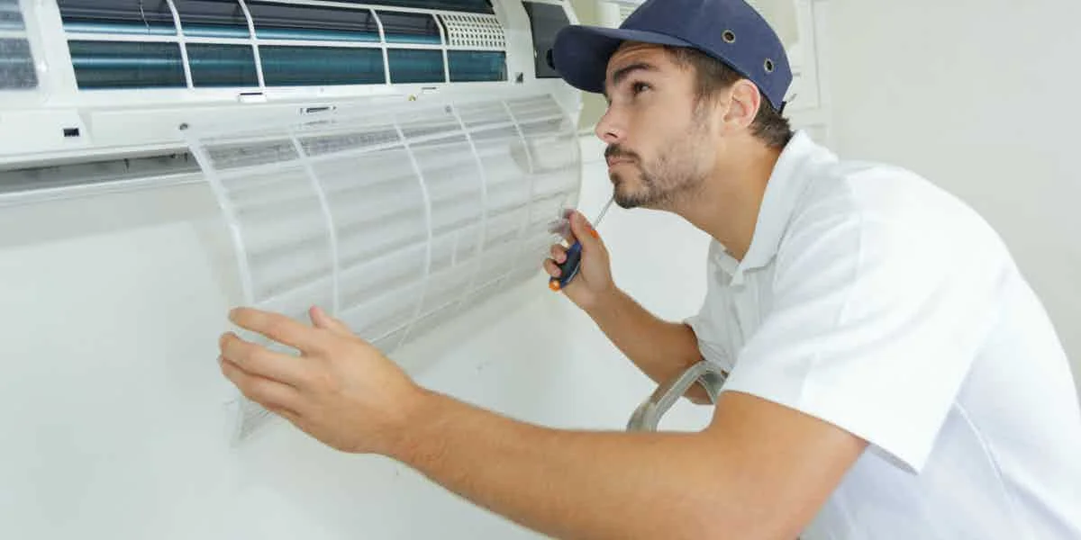 Stock photo of a technician checking airflow at an indoor air-conditioning unit